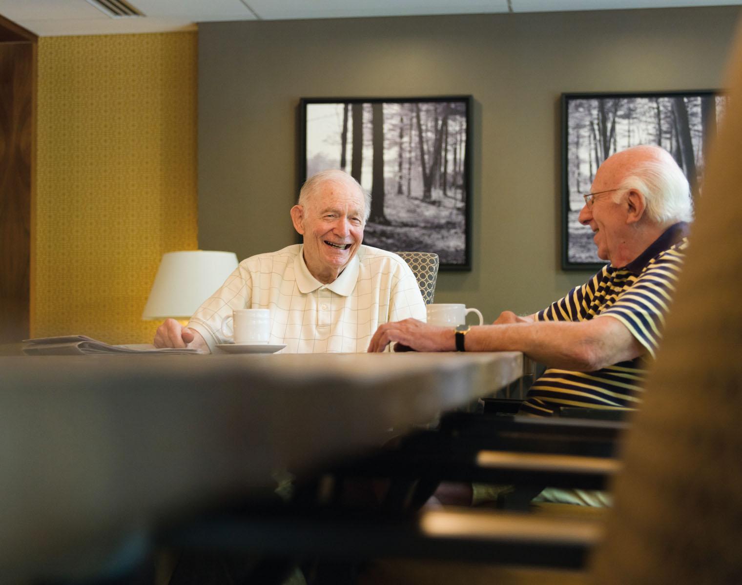 Two men enjoy a cup of coffee and a laugh.