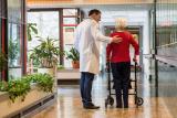 Doctor walking with older woman using a walker