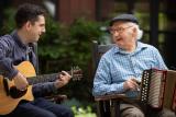 Younger man playing music with an older man