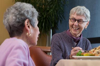 Two female friends laugh while enjoying a meal together