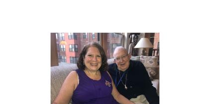 A daughter sits with her senior father in his NewBridge apartment.