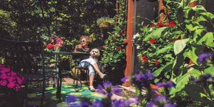 A female NewBridge resident sits in a garden with her dog.