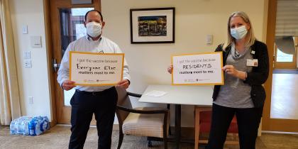 HSL employees Matt Hollingshead and Kim Brooks hold up signs saying why they received their COVID-19 vaccines.