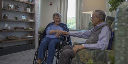 Older couple holding hands in residential facility.