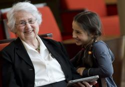 Young girl with braids instructs an older woman on how to use an ipad at a multigenerational event on the NewBridge on the Charles campus.