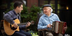 Younger man playing music with an older man