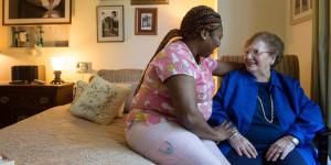 Nurse sitting with older woman in LTC