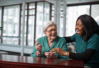 A patient at Hebrew Rehabilitation Center listens to therapeutic music with the help of a life enhancement team member.