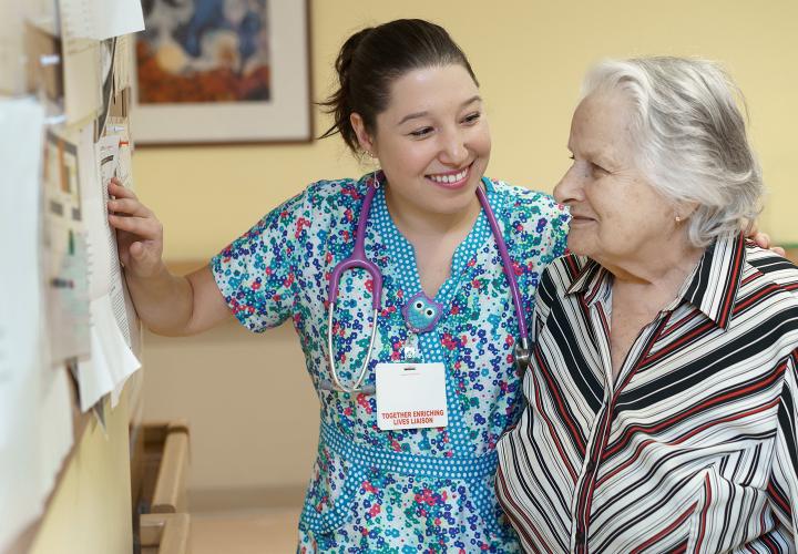 A Russian-speaking nurse at Hebrew Rehabilitation Center stands smiling with her arm around a female patient.